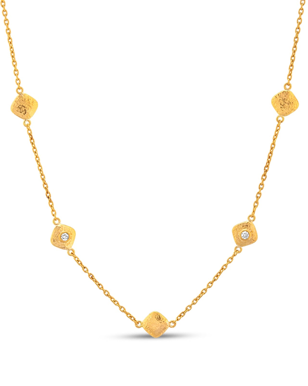 A gold necklace with multiple station charms and attached to a chain with small diamond accents.