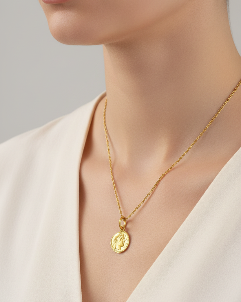 Gold necklace with a pendant worn by a model against a neutral background