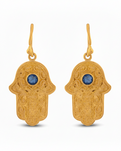 Gold Hamsa hand earrings with blue stones on a white background