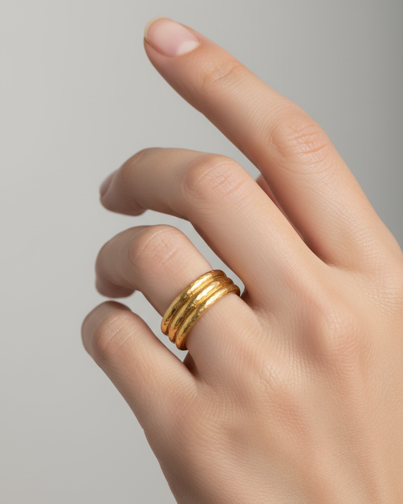 Hand wearing a gold ring on a neutral background