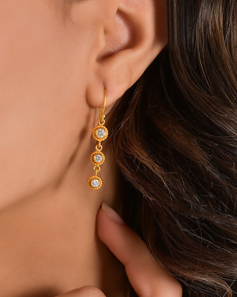 Gold earring with clear stones worn by a person