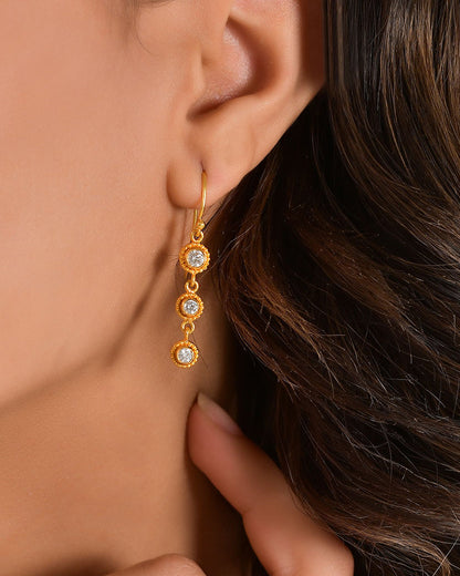 Gold earring with clear stones worn by a person