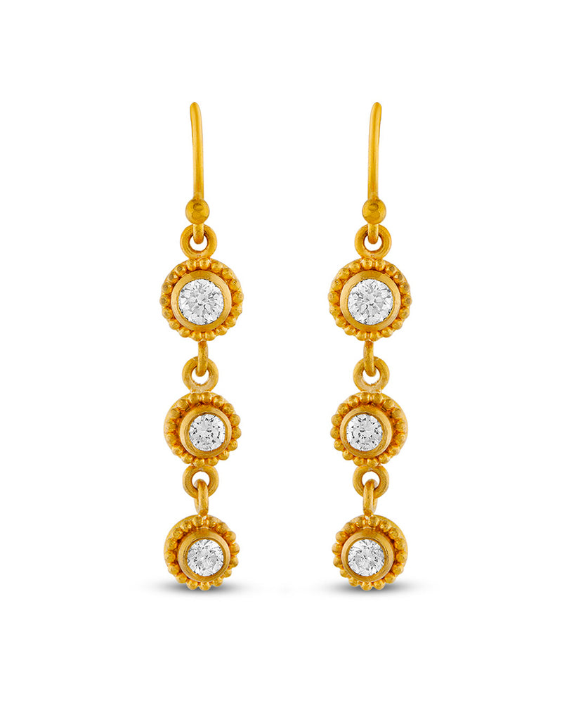 Gold earrings with circular designs and clear stones on a white background