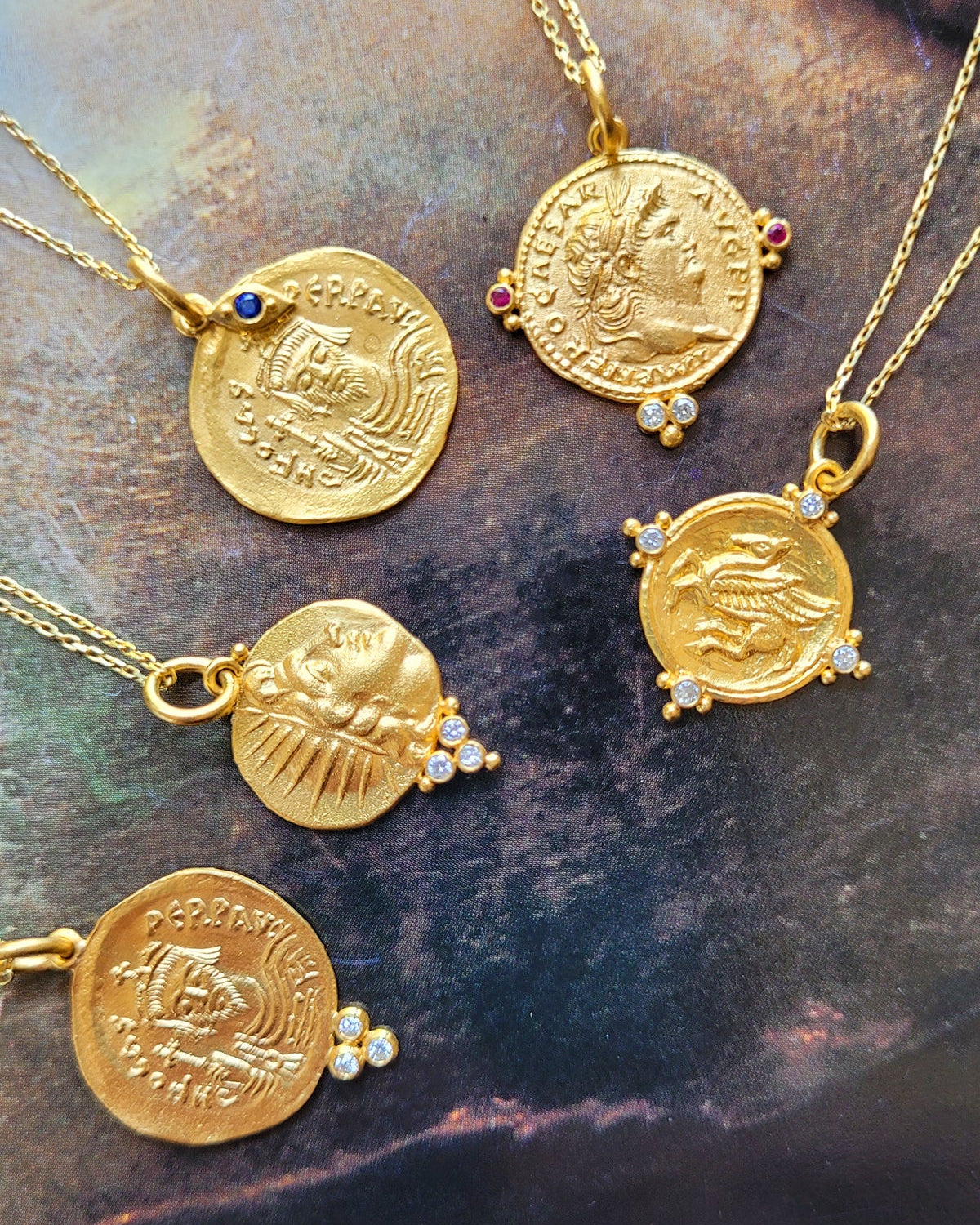 Gold coin necklaces with embedded stones on a stone surface