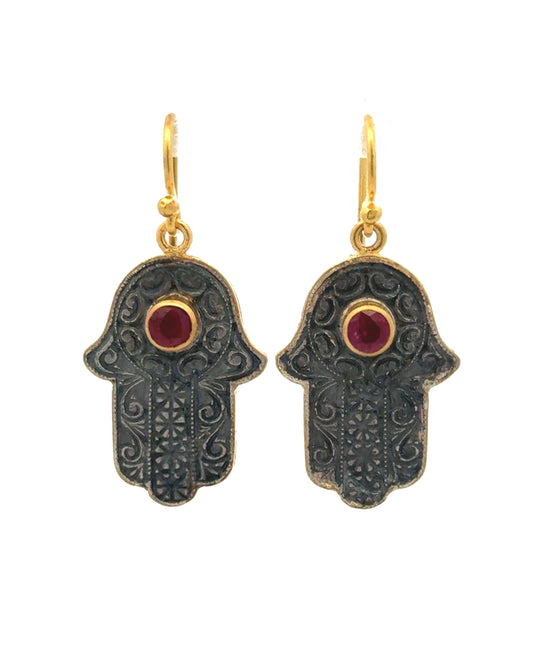 Hamsa hand earrings with gold accents and red gemstones on a white background