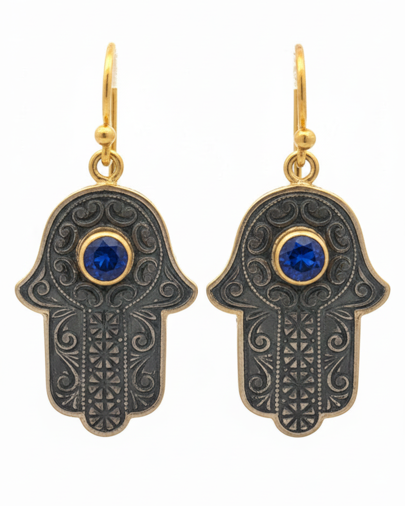 Hamsa hand earrings with blue gemstones on a white background
