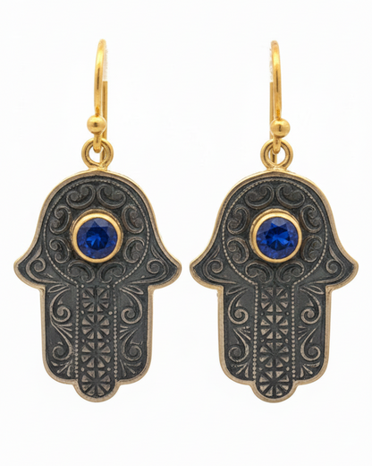 Hamsa hand earrings with blue gemstones on a white background