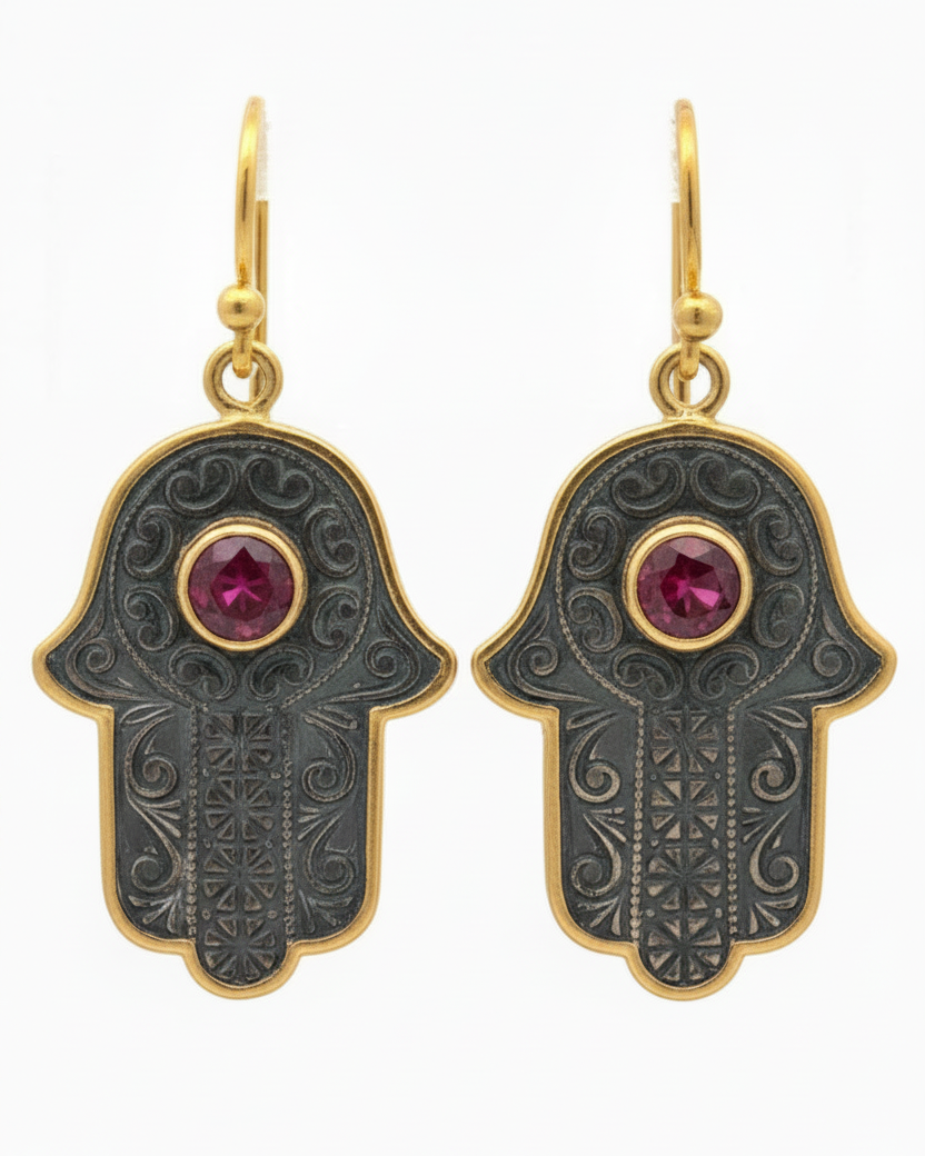 Hamsa hand earrings with gold accents and red gemstones on a white background