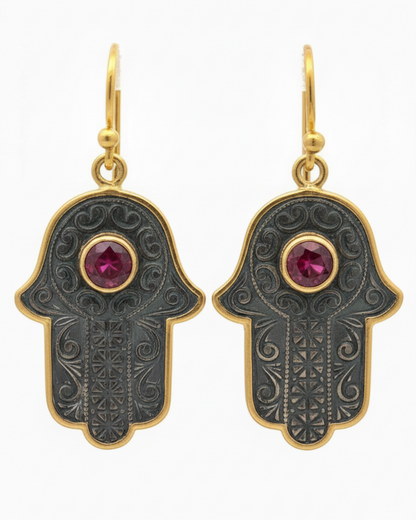 Hamsa hand earrings with gold accents and red gemstones on a white background