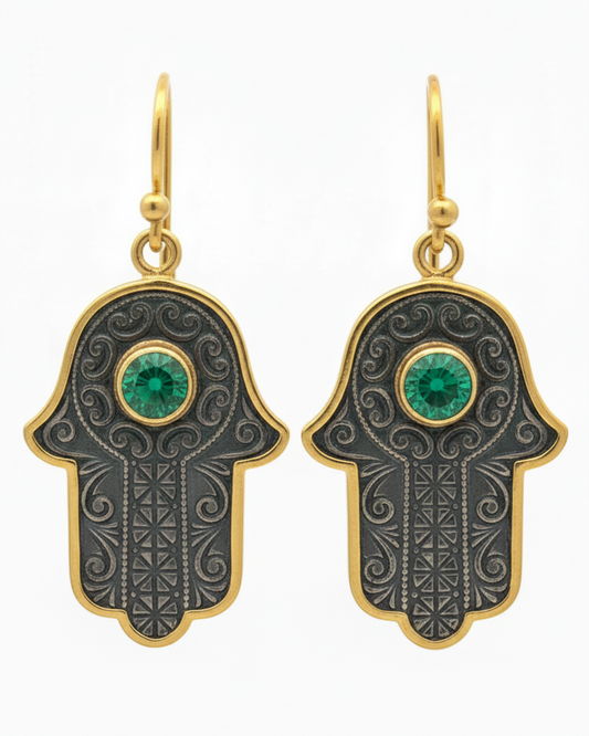 Hamsa hand earrings with green gemstones on a white background