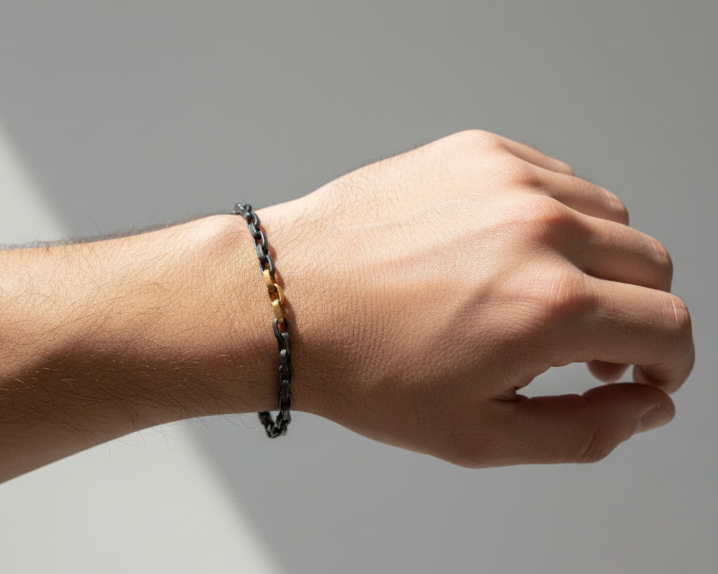Bracelet with alternating gold and silver chain links on a white background