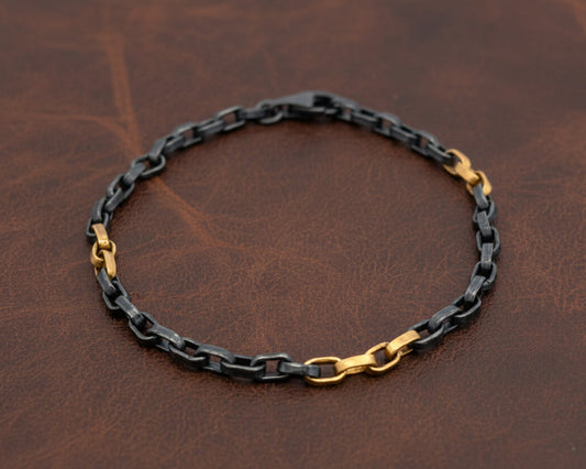 Chain bracelet with black and gold links on a white background