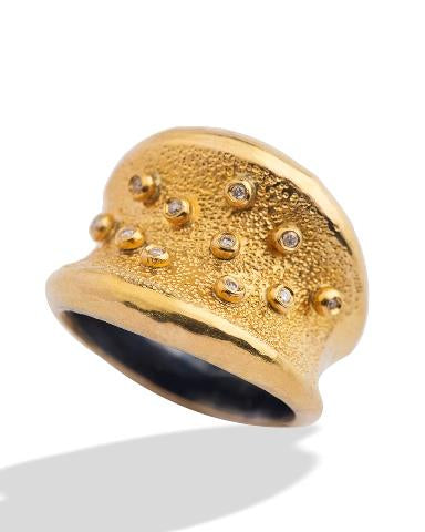 Gold ring with textured surface and embedded stones on a white background